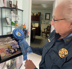 chief lucille maes looking at a picture she's holding that's adorned with a blue ribbon