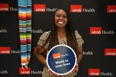 Iesha Johnson, UTMB employee, posing with sign that says "made to save lives"