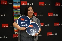 May 2 lecture series attendee posing with silly signs that say "Trust us, we're first responders." and "I'm kind of a big deal"