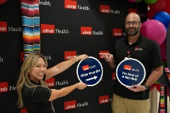 UTMB employees Stephanie Hurt and Ben Shapley posing with fun signs that say "older than dirt" and "I'm kind of a big deal"