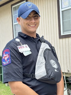 male EMT with Galveston EMS wearing a ball cap and sling backpack smiling