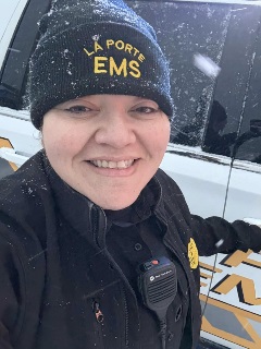 image of woman smiling wearing a beanie that says "La Porte EMS". she has on a black uniform with a radio attached