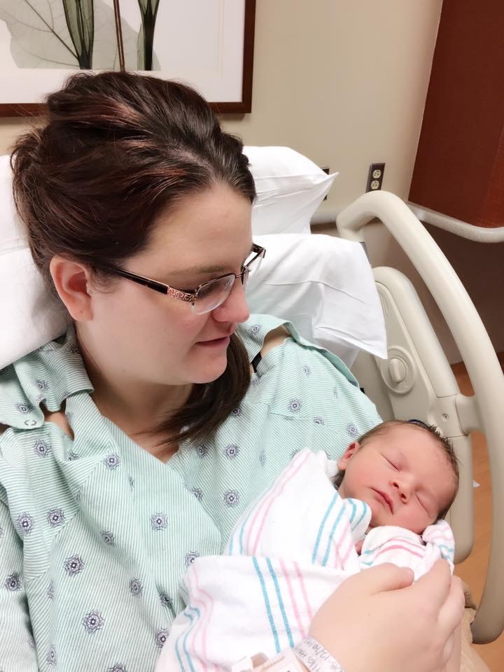 image of mom wearing hospital gown holding son wrapped in hospital blanket - they are situated in hospital bed