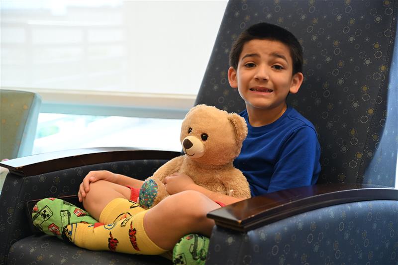 little boy holding a teddy bear in a clinic setting