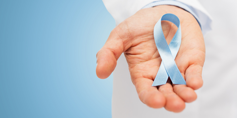 blue background with gradient fading into a hand holding a light blue cancer awareness ribbon for prostate cancer awareness