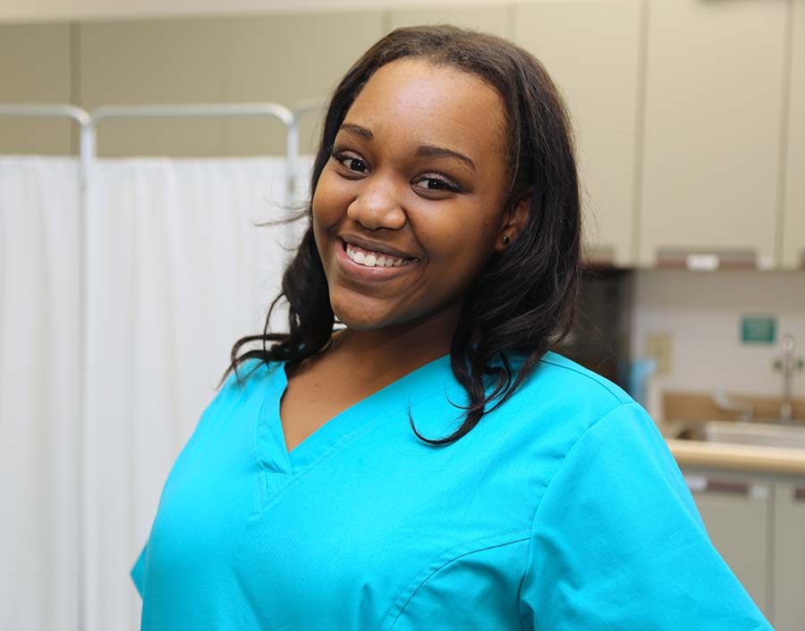 Nurse in teal scrubs smiling