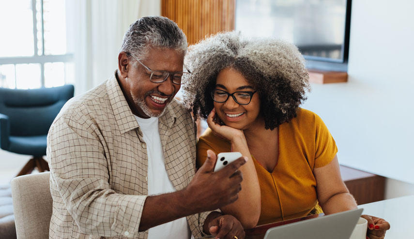 Senior couple using laptop and phone at home