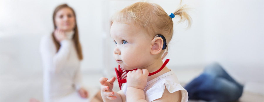A toddler with a cochlear implant participates in a pediatric therapy session.