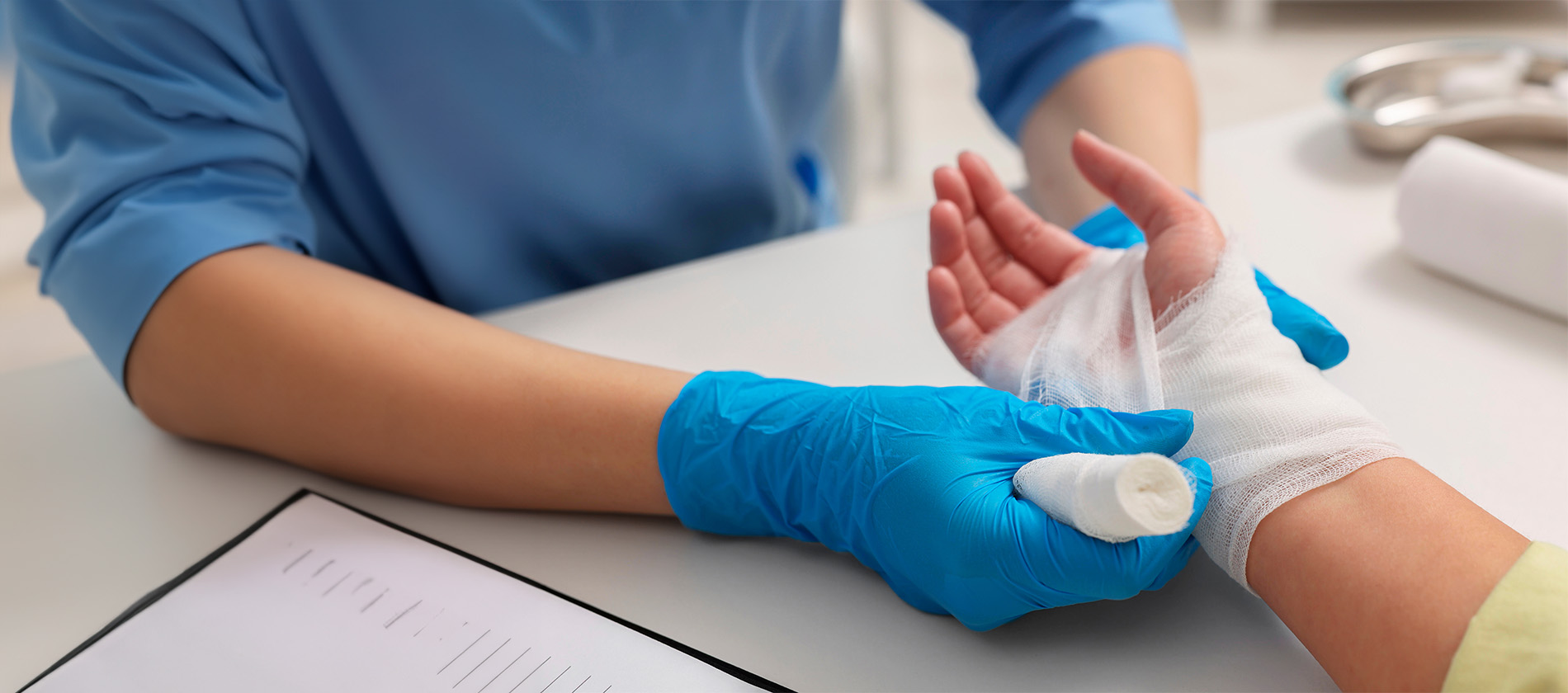 A healthcare provider wraps a patient's hand with gauze during burn wound care