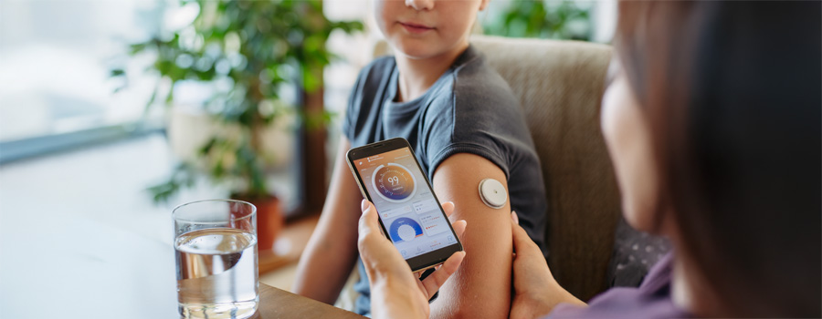 Girl with diabetes checking blood glucose level at home using continuous glucose monitor.