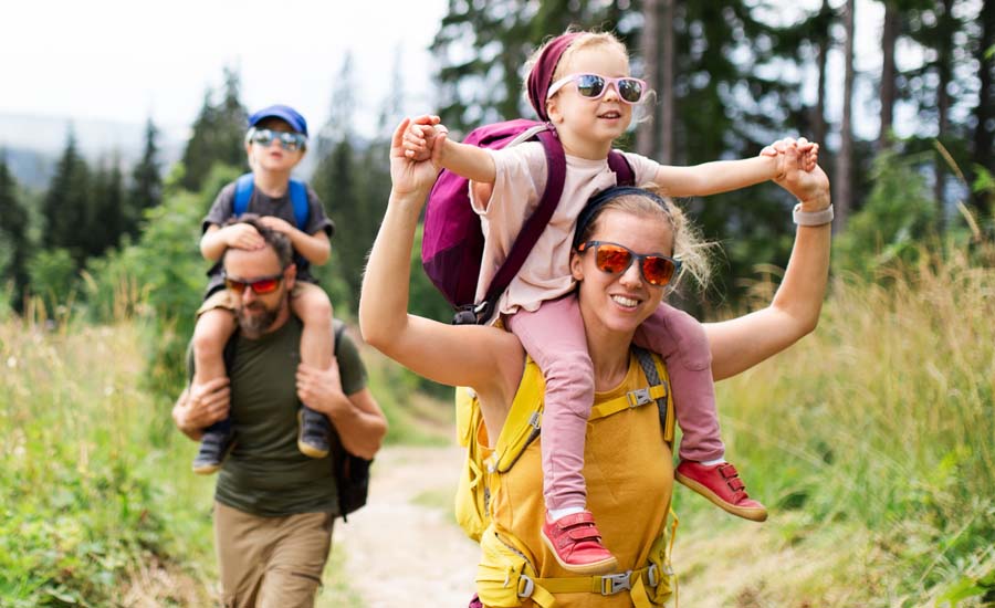 Man and woman with two small children hiking outdoors in summer nature