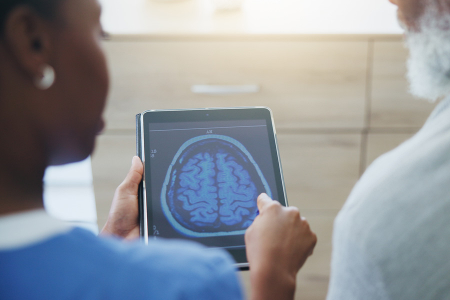 A healthcare provider reviews brain imaging results with an older adult during a neurology consultation.