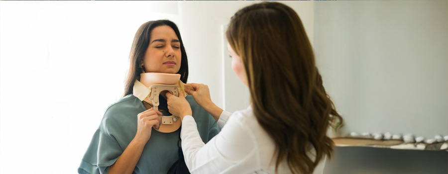 Female doctor at UTMB gently applying a cervical collar to a female patient with neck pain following an accident