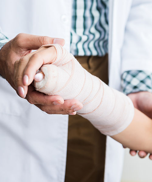 Close up of a doctor examining a person's wrapped, injured hand