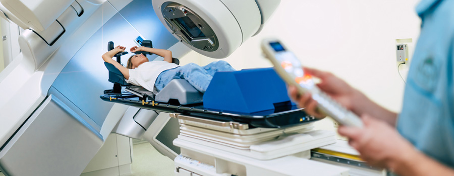 A patient receives radiation therapy as a provider operates the machine, showcasing the precision technology used in modern cancer treatment.
