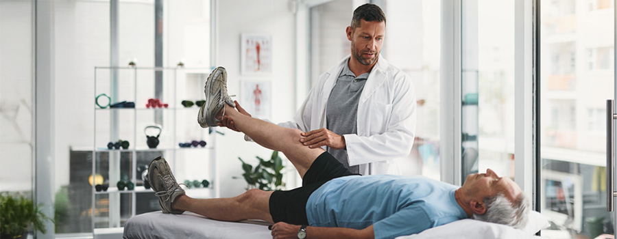 Physical therapist lifting patient’s leg during therapy session