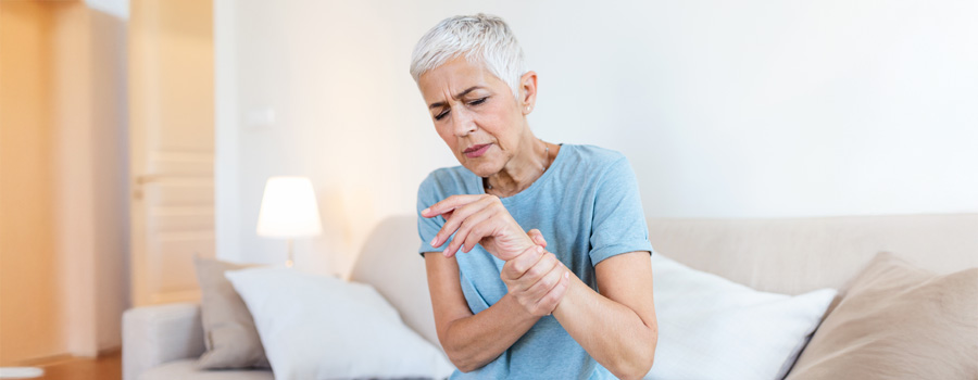 Seated elderly woman in arthritis pain, holding her wrist