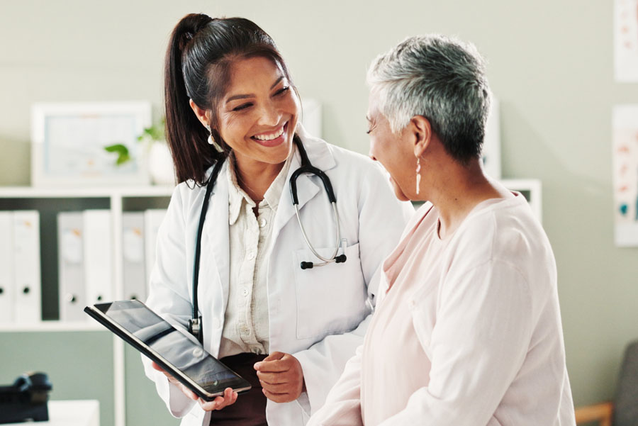 Female doctor showing a tablet to a female patient in a healthcare setting