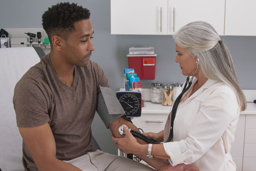 Man getting his blood pressure checked by a female doctor at urgent care