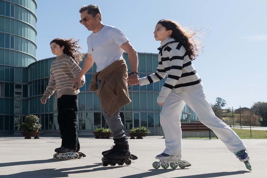 Father roller blading with his two teen daughters in city square on a sunny day