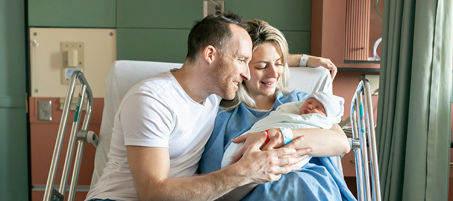 Parents hold their newborn together in a mother baby unit room at UTMB Health Labor and Delivery Clear Lake.