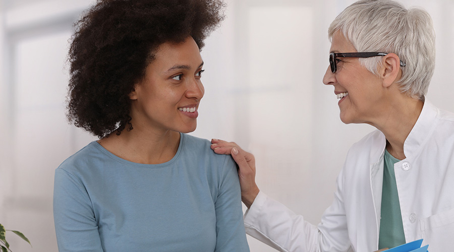 A UTMB gynecologist smiles and talks with a patient during a routine visit.