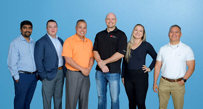 Five men and one woman in casual and business attire pose together in front of a blue background.