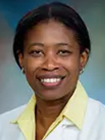 Dr. Esosa Odigie-Okon normal head-and-shoulders portrait of a woman with short dark hair wearing a white lab coast over a yellow shirt