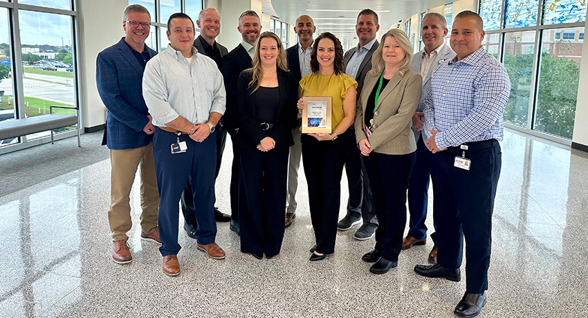 A group of 11 leaders from the UTMB Information Technology Services department stand in a group as one person holds the plaque they were awarded for being named a Most Wired healthcare institution.