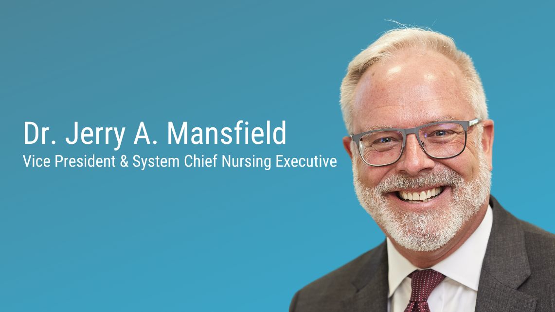 Text on a blue background reading “Dr. Jerry A. Mansfield, Vice President & System Chief Nursing Executive,” shown beside a person in a suit and tie.