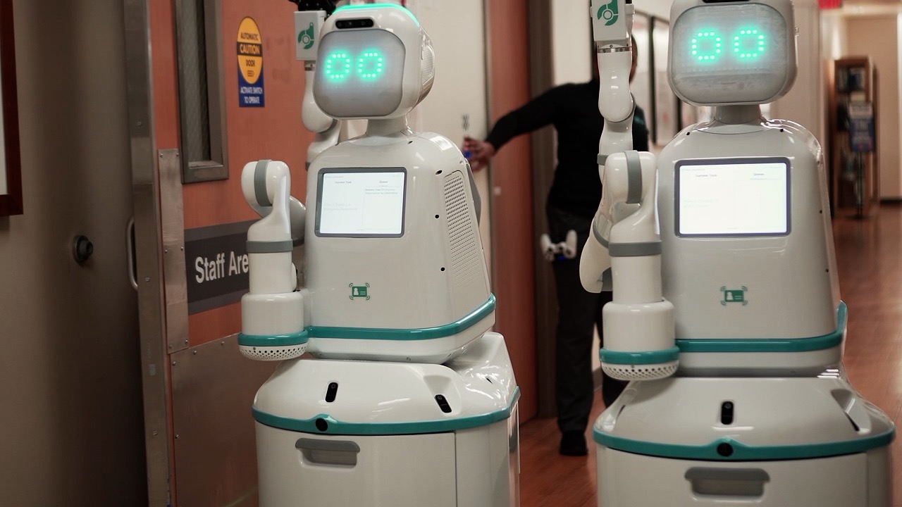Twofive foot tall white robots in a hospital hallway
