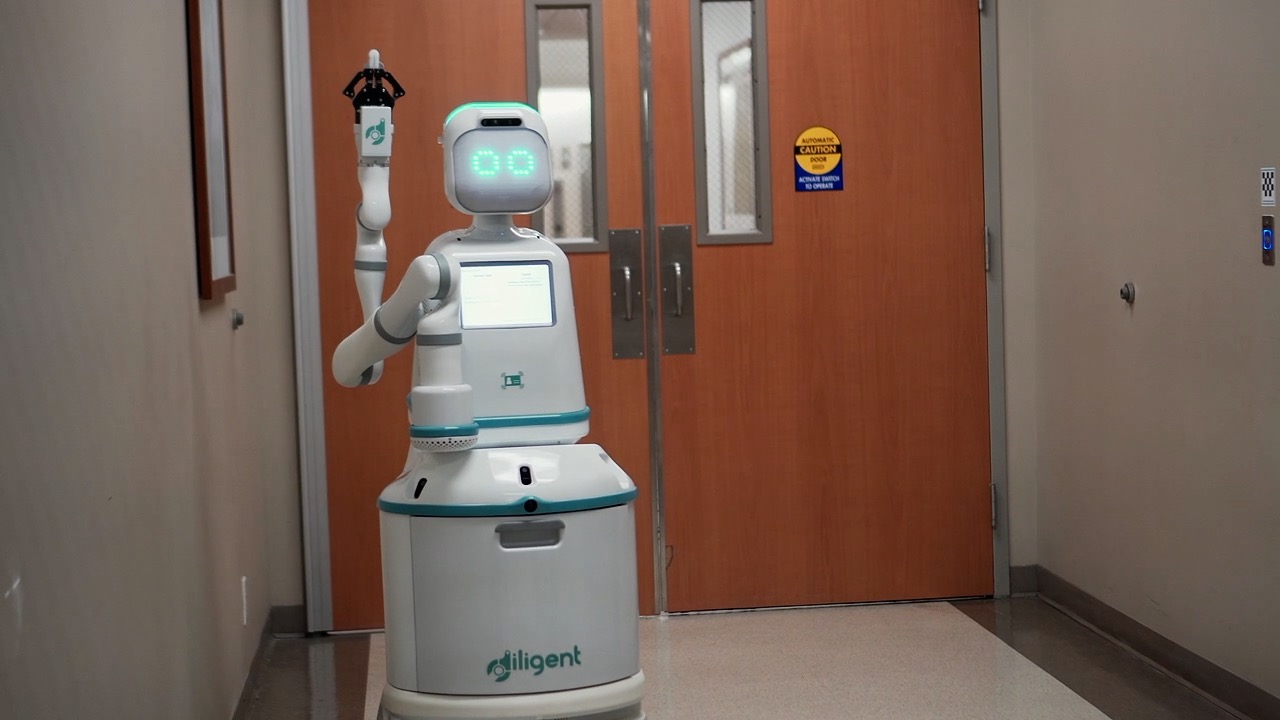 A five foot tall white robot in a hospital hallway