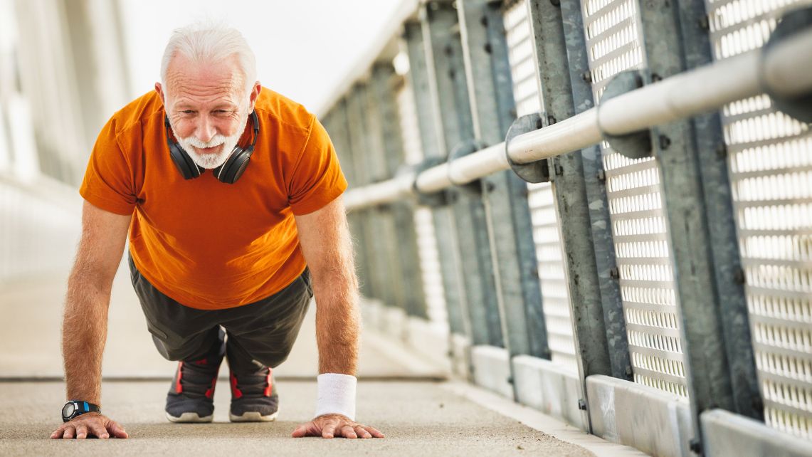 An older man doing push ups on the sidewalk