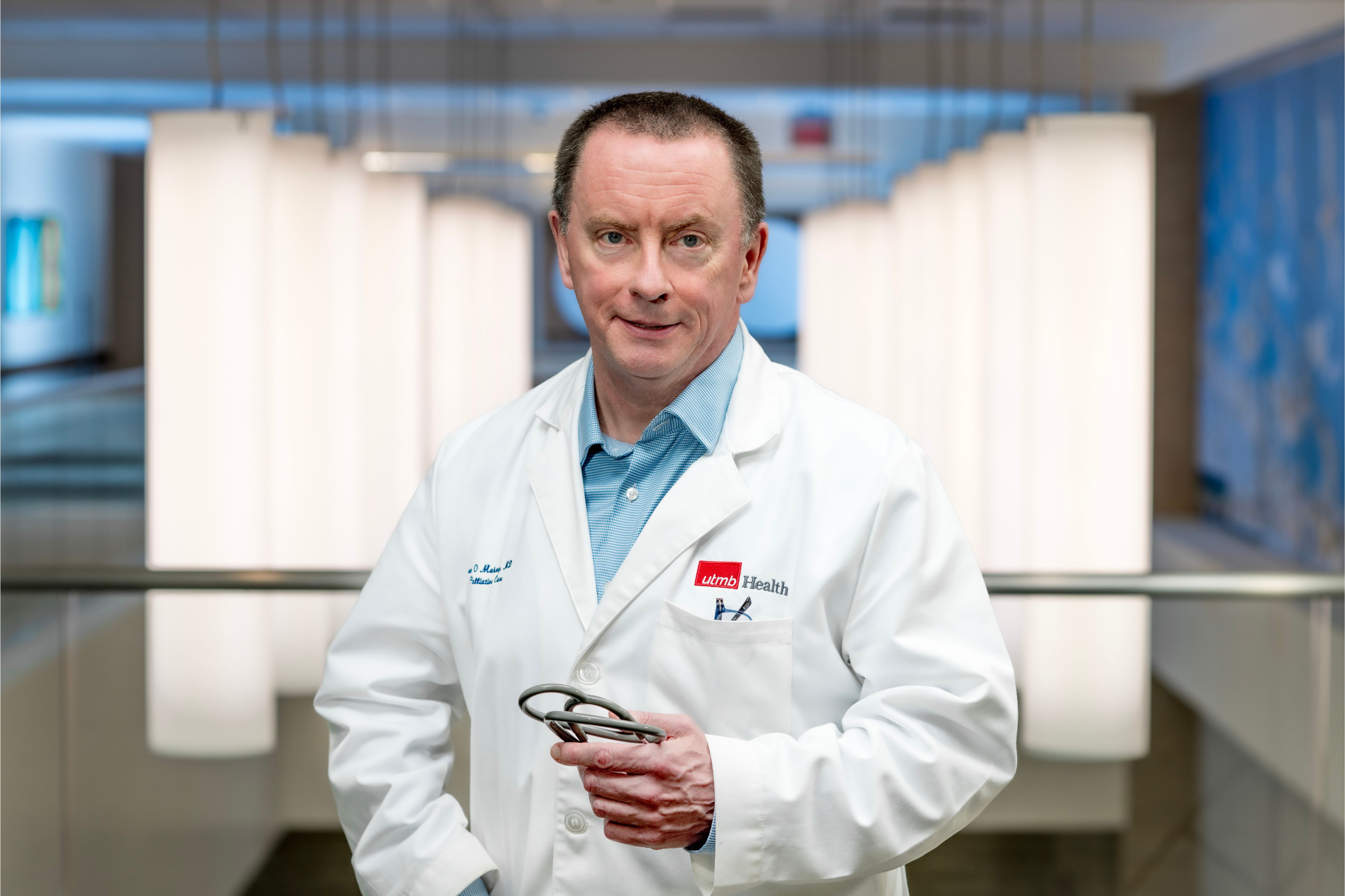Dr. Sean O’Mahony, director of the Palliative Medicine division at UTMB, wearing a white coat and holdiing a stethescope