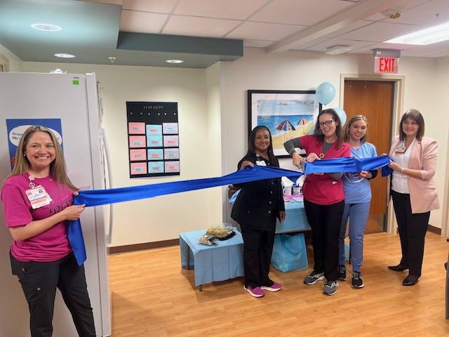 UTMB employees hold a blue ribbon while one fo the employees cuts it to celebrate the establishment of a milk bank at the Jennie Sealy Hosptial.
