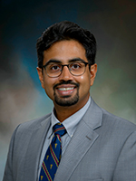 Dr. Raj Vaghjiani is an assistant professor of surgical oncology at UTMB. Dr. Raj Vaghjiani, wearing a gray suit and blue, red, and gold tie appears in a headshot.