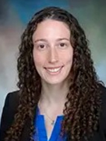 Formal headshot of woman with long dark hair, blue blouse and black jacaket