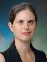 Headshot of woman in black shirt with pulled back brown hair