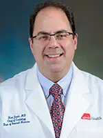 Man with dark hairr and glasses wearing a white lab coat