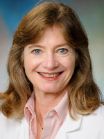 Formal headshot of a woman with light brown hair wearing a white lab coat