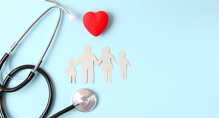 Stethoscope, red heart, and paper cutout figures of a family arranged on a light blue background, symbolizing comprehensive family health care and preventive medical services