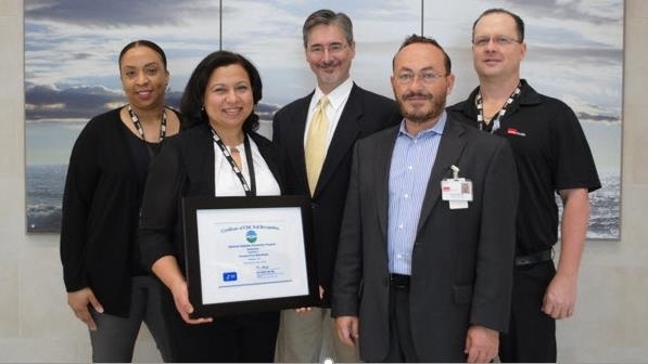 Five UTMB Health professionals stand together in a clinical setting holding a framed CDC certificate recognizing the Diabetes Prevention Program